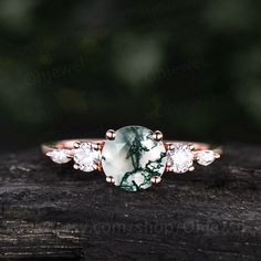 a green and white ring sitting on top of a piece of wood with diamonds around it