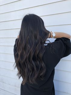 the back of a woman's head with long, wavy hair in front of a white house