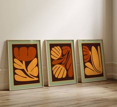 three framed art pieces sitting on top of a wooden floor