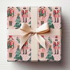 a present wrapped in pink wrapping paper with a gold bow and nutcrackers on it