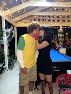 a man and woman kissing in front of a pool table