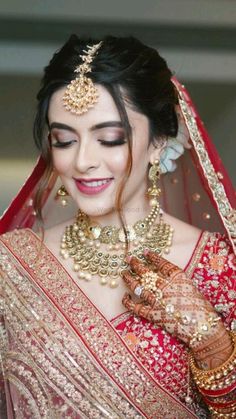 a woman in a red and gold bridal outfit with her hands on her chest