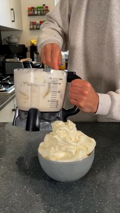 a person is mixing whipped cream in a bowl with a blender on the counter