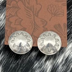 This is a very cute pair of vintage Navajo-made sterling silver screwback earrings. The earrings feature a pointed domed shape, with a circle of charming decorative leaf stampings that form a delicate floral design. These elegant details highlight the fine craftsmanship typical of Navajo jewelry. Each screwback is stamped "STERLING," confirming their authenticity. With a diameter of 1 inch and a total weight of 10.4 grams, these earrings are a lovely example of 1960s Native American artistry, pe Silver Concho Earrings For Gift, Silver Concho Earrings As A Gift, Decorative Silver Earrings As Gift, Elegant Silver Concho Earrings, Silver Southwestern Round Earrings, Vintage Sterling Silver Earrings Stamped 925, Traditional Concho Earrings For Gift, Traditional Concho Earrings As Gift, Artisan Concho Earrings As Gift