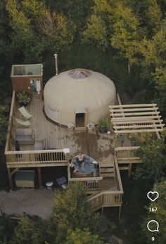 an aerial view of a yurt in the woods with people sitting on decking