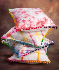 three pillows stacked on top of each other with pom - poms around them