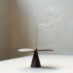 "Embrace tranquility and elegance with our Handcrafted Curved Incense Holder, a perfect fusion of natural black walnut wood and gleaming brass accents. This artisanal piece, with its unique curved design, invites a sense of calm and sophistication into any living space or meditation area. Material: Black Walnut Wood + Brass Size: Disc Diameter: 4.72\" (12cm), Height: 2.36\" (6cm) Finish: Natural Wood Curve, Brass Sphere Detail Key Features: 🌊 Fluid Design: The incense holder's disc is expertly thinned to embrace the natural bending of wood, creating an elegant arc that mirrors the ebb and flow of nature. 🌤️ Responsive Craftsmanship: Each holder is designed to respond to environmental changes, allowing the wood to form a unique curvature over time, a dance with nature's own design. 👣 Wab Unique Incense Holder, Wood Incense Holder, Wabi Sabi Home Decor, Nature Materials, Wabi Sabi Aesthetic, Meditation Area, Fluid Design, Black Walnut Wood, Ceramic Ideas