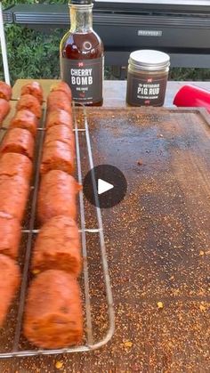 hotdogs on a grill with ketchup, mustard and seasoning next to them