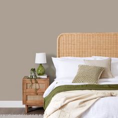 a bed with white linens and green throw pillows on it, next to a wooden night stand