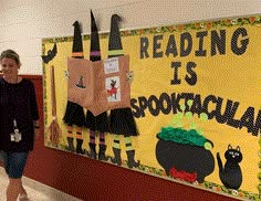 a woman walking past a bulletin board with witches on it and reading is spookkrara