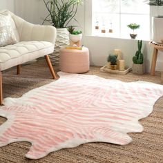 a pink and white rug in a living room next to a window with potted plants