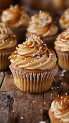 some cupcakes with frosting and sprinkles sitting on a wooden table