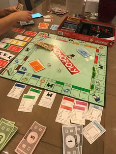 a monopoly board game on a table with money and cards scattered around it, as people play the game