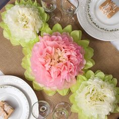 the table is set with plates, silverware and pink flowers on top of it