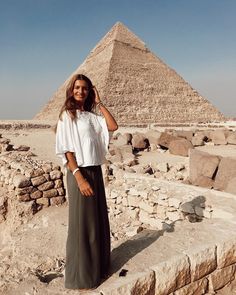 a woman is standing in front of the pyramids