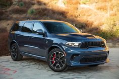 the new dodge duran is parked in front of some brushy hills and trees,