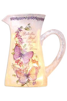 a glass pitcher with butterflies and flowers on the side, lit up by a light