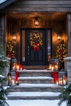 christmas wreaths on the front steps of a house with lit candles and evergreen trees