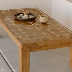 a wooden table topped with a bowl of rocks next to a cup and saucer