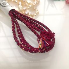 a red beaded necklace with tassels and beads on the table next to it