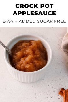 a bowl filled with crock pot applesauce next to cinnamon sticks and an apple slice