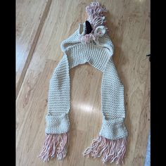 a white scarf with pink tassels laying on top of a wooden floor