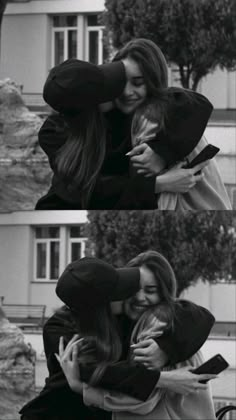 two women hugging each other in front of a building and one woman is holding her head