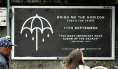 two people standing in front of a sign that says bring me the horizon, that's the spirit