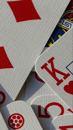 several playing cards stacked on top of each other with red and white symbols all over them