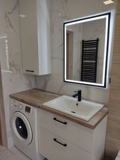 a washer and dryer in a bathroom with a large mirror above the sink