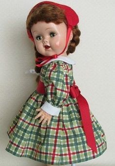 the doll is wearing a green dress with red trims and a red headband