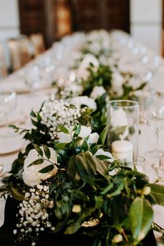 a long table with white flowers and greenery