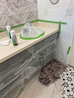 a bathroom counter is covered with plastic and some other items to be used for painting