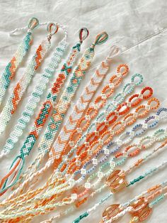 a bunch of different colored bracelets on a white tablecloth with some beads in the middle