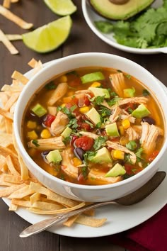 a bowl of chicken tortilla soup with avocado and cilantro