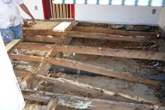 a man standing in the middle of a room that has been torn down and is surrounded by wood planks