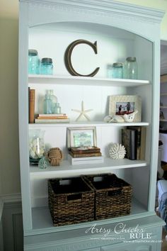 a white book shelf with baskets and books on it's shelves, along with other items