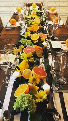 a long table with oranges and other fruits on it, along with place settings