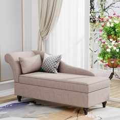 a beige chaise lounger sitting on top of a wooden floor next to a potted plant