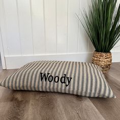 a striped pillow sitting on top of a wooden floor next to a potted plant