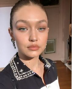 a woman with blue eyes and black shirt posing for the camera in front of a mirror