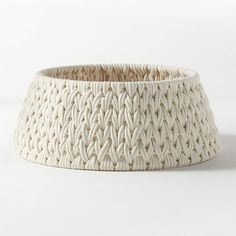 a large white basket with braiding on the sides and bottom, sitting against a white background