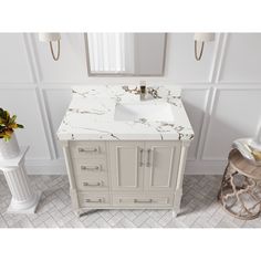 a white bathroom vanity with marble top and sink in front of two vases on the floor