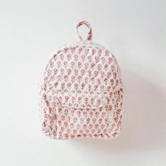 a pink and white floral backpack hanging on a wall with the tag attached to it