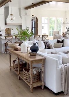 a living room filled with white furniture and lots of pillows on top of it's couches