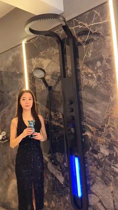 a woman taking a selfie in front of a shower with blue lights on it