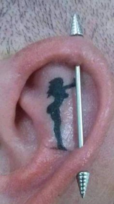 a man with some piercings on his ear and behind the ear is a silhouette of a girl