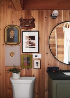 a bathroom with wood paneling and pictures on the wall, including a white toilet