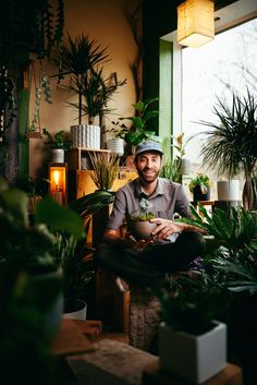 a man is sitting in front of some plants