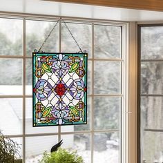 a stained glass window hanging from the side of a house with potted plants in front of it